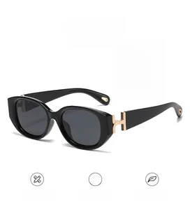 Detailed close-up of golden H-shaped metal hinge on black cat-eye sunglasses