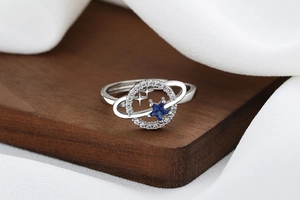 Detailed close-up of a silver celestial ring with blue star gems on a wooden display