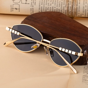 Dettaglio di occhiali da sole cat eye con aste dorate geometriche su sfondo vintage