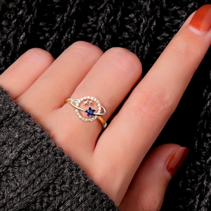 Detail shot of a star-themed ring with blue center stone and gold planet rings