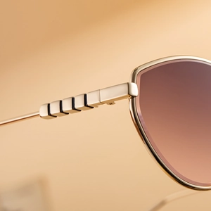 Dettaglio degli occhiali cat-eye dorati con lenti sfumate e aste metalliche decorate
