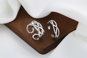 Detailed view of woven 925 silver plated open rings on a wooden tray with silk fabric
