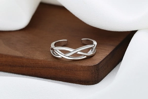 Close-up of twisted 925 silver plated ring with adjustable open band on wood texture