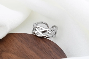 Macro shot of silver braided mesh ring on dark wood and white fabric background