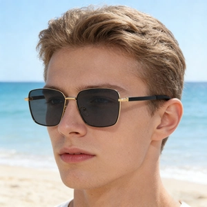 Men's square polarised sunglasses with gold metal frame worn by a model on the beach