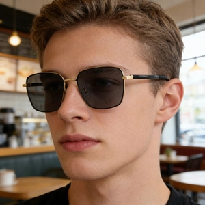 Close-up of stylish men's square polarized sunglasses with gold metal frame on a male model