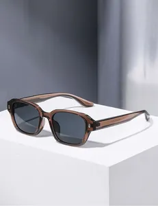 Detail view of square transparent brown sunglasses with metal hinges on a white stand
