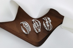 Detailed view of three silver spinner rings with rotating beads on a wood stand