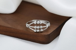 Macro detail of silver-toned abacus ring with sliding beads on triple-layered bands