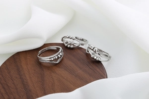 Detailed view of three silver spinner rings with beads on a dark wood and silk display