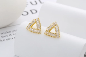 Macro detail of golden triangle stud earrings with clear rectangular cubic zirconia inlay