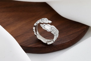 Detailed view of silver feather ring with delicate textures on a wooden stand