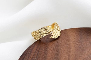 Detailed view of golden feather ring with realistic textures on a wooden stand