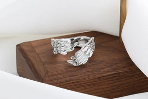 Macro shot of silver feather ring with detailed textures on elegant wooden stand