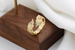 Macro shot of detailed golden feather wings on an adjustable open ring design