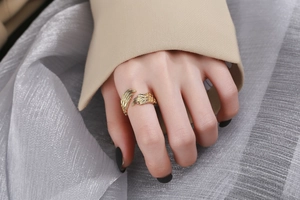 Detailed view of an adjustable golden feather ring with realistic wing texture on hand