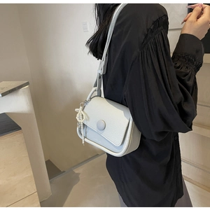 Detail of lychee pattern leather saddle bag with pearl tassel and round buckle