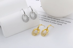 Close-up of elegant oval drop earrings with shimmering pavé set white crystals in gold and silver