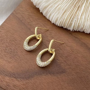Detail of gold oval hoop earrings with sparkling cubic zirconia on wood surface