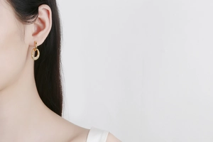 Close-up of golden double-hoop earrings with micro-pave crystals on a model's ear