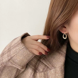 Detail of elegant gold double-loop earrings with small pavé crystals on a female model
