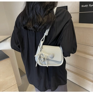Close-up of litchi grain leather saddle bag with pearl heart charm on a model back