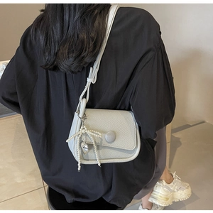 Detail of light gray lychee pattern saddle bag with pearl bow charm worn over the shoulder