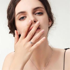 Close-up of minimalist silver heart jewelry set featuring hollow ring and stud earrings