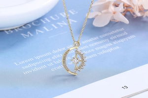 Detail of gold crescent moon and star pendant with pave-set crystals on a fine chain
