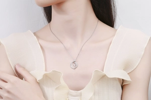 Detail of silver sun moon pendant necklace with crystals on model wearing white ruffle top