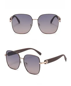 Détail des lunettes de soleil carrées avec verres dégradés violets et monture dorée