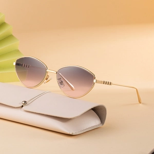 Occhiali da sole cat-eye dorati con lenti sfumate su custodia in pelle color beige