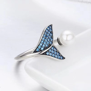 Detail of silver fish tail ring featuring sparkling blue pavé zircons and a white pearl