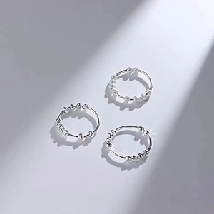 Three minimalist silver anti-anxiety rings with sliding beads on a grey background