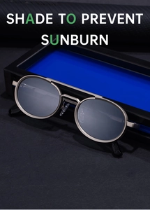 Close-up of retro oval metal frame sunglasses with dark grey lenses on a blue display box