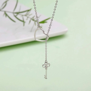 Close-up of silver Y-shaped necklace with heart-shaped buckle and small key pendant