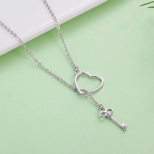 Detail showing the polished silver infinity key pendant and heart link on a delicate chain