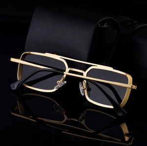 Detail of square gold metal sunglasses with dark lenses on a black leather case