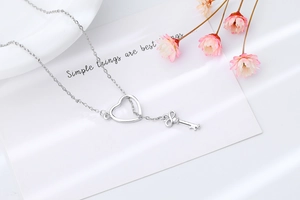 Detail of silver key necklace with heart infinity pendant on a decorative card