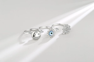 Macro detail of silver spinning ring set featuring clover, evil eye, and star motifs