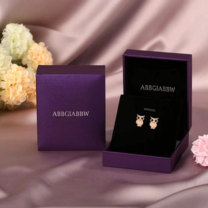 Rose gold owl stud earrings with black bead eyes on purple silk gift box with flowers