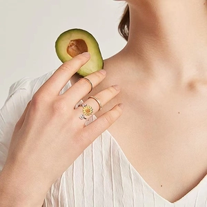 Rotating sunflower ring with crystal letter B shown on model's hand with avocado