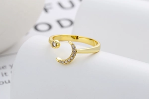 Close-up of golden moon ring with sparkling crystals on a minimalist wave stand