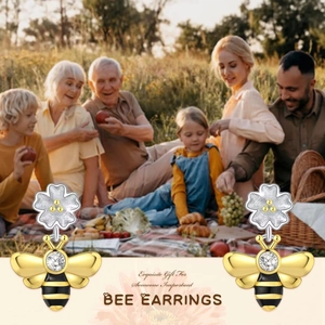 Détail de boucles d'oreilles abeille avec fleurs argentées et pendentifs dorés
