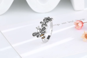 Detailed close-up of bee and daisy ring with orange zircons and sparkling crystals
