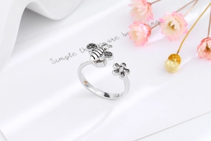 Macro shot of silver spinning bee and daisy open ring with vintage crystal details