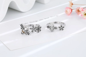 Detailed close-up of vintage silver spinner rings with bee and daisy flower motifs