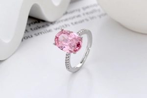 Vue macro d'une bague avec pierre ovale rose et serti micro-pave argenté sur fond blanc