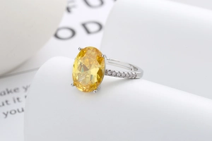 Vue macro d'une bague avec gemme jaune ovale, diamants micropavé et serti à quatre griffes