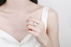 Gros plan d'une bague diamant rose taille poire avec monture halo sur le doigt